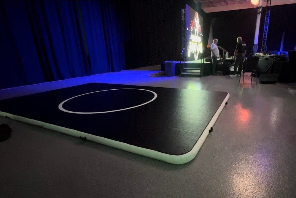 A 10 by 16 Pro FlowMat rolled out on an arena floor in front of a stage